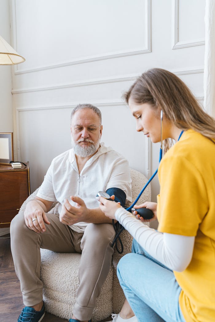 A healthcare professional checks an elderly mans blood pressure in a cozy room.
